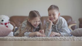 Kopplar samman förtjusande litet för stående pojke- och flickalögn på mattan och att hålla ögonen på något som är rolig på datore stock video Kopplar samman förtjusande litet för stående pojke- och flickalögn på mattan och att hålla ögonen på något som är rolig på datore stock video