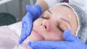 Kosmetiker setzt die Creme auf das Gesicht der Frau Cosmetologistgesichtsbehandlung Nahaufnahme stock video footage Kosmetiker setzt die Creme auf das Gesicht der Frau Cosmetologistgesichtsbehandlung Nahaufnahme stock video footage