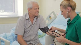 Krankenschwester misst Blutdruck des männlichen Patienten stock video footage Krankenschwester misst Blutdruck des männlichen Patienten stock video footage