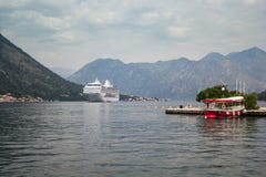 Kreuzschiff in der Bucht zwischen den Bergen, das Taxiboot am Pier im Vordergrund stockbild Kreuzschiff in der Bucht zwischen den Bergen, das Taxiboot am Pier im Vordergrund stockbild
