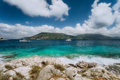 Kristallklart genomskinligt blått vatten för turkoskrickamedelhav i den Fiskardo staden Vit yacht i det öppna havet på Royaltyfri Bild Kristallklart genomskinligt blått vatten för turkoskrickamedelhav i den Fiskardo staden Vit yacht i det öppna havet på Royaltyfri Bild