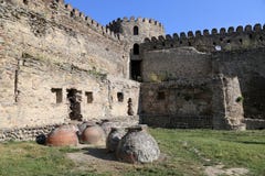 Kvevri antico - navi dell'argilla per produrre vino, sepolte nella terra sotto la parete della fortezza vicino alla cattedrale di immagini stock libere da diritti Kvevri antico - navi dell'argilla per produrre vino, sepolte nella terra sotto la parete della fortezza vicino alla cattedrale di immagini stock libere da diritti