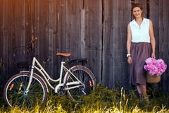 Kvinna med buketten av pioner och cykeln royaltyfria foton Kvinna med buketten av pioner och cykeln royaltyfria foton