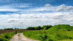 Kvinna som går i bygden under molnig himmel fotografering för bildbyråer Kvinna som går i bygden under molnig himmel fotografering för bildbyråer