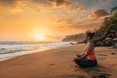 Kvinna som gör yoga på stranden - Padmasana lotusblomma poserar fotografering för bildbyråer Kvinna som gör yoga på stranden - Padmasana lotusblomma poserar fotografering för bildbyråer