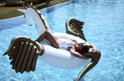 kvinna som kopplar av i lyxigt simbassängsemesterorthotell på den stora uppblåsbara enhörningen som svävar den pegasus flötet fotografering för bildbyråer kvinna som kopplar av i lyxigt simbassängsemesterorthotell på den stora uppblåsbara enhörningen som svävar den pegasus flötet fotografering för bildbyråer
