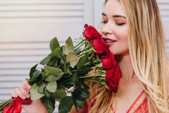 Kvinna som luktar buketten av röda rosor royaltyfri fotografi Kvinna som luktar buketten av röda rosor royaltyfri fotografi