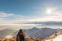 Kvinnafotvandrare som vilar på bergöverkant Bakre sikt, vinterlivsstil, kall känsla, solstjärna i panelljus royaltyfri fotografi Kvinnafotvandrare som vilar på bergöverkant Bakre sikt, vinterlivsstil, kall känsla, solstjärna i panelljus royaltyfri fotografi