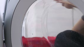 Kvinnan i röda gummihandskar tvättar en tvättmaskin med svampen lager videofilmer Kvinnan i röda gummihandskar tvättar en tvättmaskin med svampen lager videofilmer