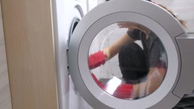 Kvinnan i röda gummihandskar tvättar en tvättmaskin med svampen lager videofilmer Kvinnan i röda gummihandskar tvättar en tvättmaskin med svampen lager videofilmer