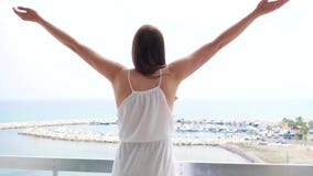 Kvinnan på semesterlönelyft beväpnar upp på terrass med havssikt Outstretching händer för kvinnlig i ultrarapid lager videofilmer Kvinnan på semesterlönelyft beväpnar upp på terrass med havssikt Outstretching händer för kvinnlig i ultrarapid lager videofilmer