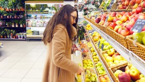 Kvinnan som väljer nya röda äpplen i livsmedelsbutik, producerar avdelning och att sätta den i plastpåse Den unga nätta flickan ä arkivfoton Kvinnan som väljer nya röda äpplen i livsmedelsbutik, producerar avdelning och att sätta den i plastpåse Den unga nätta flickan ä arkivfoton