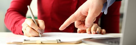 Kvinnlig anst?lld som rymmer silverpennan som g?r anm?rkningar i dokument arkivbild Kvinnlig anst?lld som rymmer silverpennan som g?r anm?rkningar i dokument arkivbild