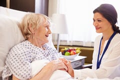 Kvinnlig patient för doktor Talking To Senior i sjukhussäng arkivbild Kvinnlig patient för doktor Talking To Senior i sjukhussäng arkivbild