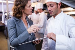 Kvinnlig restaurangchefhandstil på skrivplattan, medan påverka varandra till den head kocken fotografering för bildbyråer Kvinnlig restaurangchefhandstil på skrivplattan, medan påverka varandra till den head kocken fotografering för bildbyråer