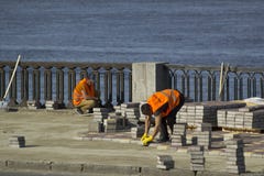 Kyiv Ukraine - 21.04.2018: two workers in orange uniform repairing bridge road with concrete paver stock photo Kyiv Ukraine - 21.04.2018: two workers in orange uniform repairing bridge road with concrete paver stock photo