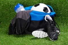 Kängor, fotbollbollen, T-tröja och en vattenflaska, i sportar hänger löst, mot bakgrunden av gräs arkivfoton Kängor, fotbollbollen, T-tröja och en vattenflaska, i sportar hänger löst, mot bakgrunden av gräs arkivfoton