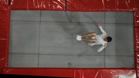 L'acrobata della ginnasta di vista superiore in vestiti bianchi esegue un salto mortale su un trampolino al rallentatore archivi video L'acrobata della ginnasta di vista superiore in vestiti bianchi esegue un salto mortale su un trampolino al rallentatore archivi video