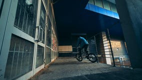 L'adolescent masculin fait un cascade sur sa bicyclette dans un bâtiment vide banque de vidéos L'adolescent masculin fait un cascade sur sa bicyclette dans un bâtiment vide banque de vidéos