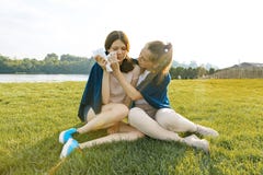 L'adolescente la soulage pleurant, amie contrariée et triste Les filles s'asseyent sur l'herbe verte en parc image libre de droits L'adolescente la soulage pleurant, amie contrariée et triste Les filles s'asseyent sur l'herbe verte en parc image libre de droits