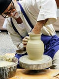 L'artigiano senior fila le terraglie sulla sua ruota alla fiera del mestiere a Bratislava immagini stock L'artigiano senior fila le terraglie sulla sua ruota alla fiera del mestiere a Bratislava immagini stock