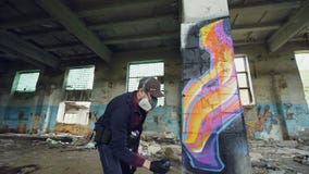 L'artista urbano della via sta dipingendo i graffiti in costruzione abbandonata con le pareti sporche e finestre, sta usando lo s archivi video L'artista urbano della via sta dipingendo i graffiti in costruzione abbandonata con le pareti sporche e finestre, sta usando lo s archivi video