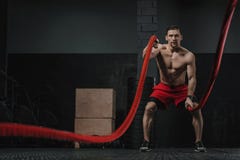 L'athlète de Crossfit faisant des cordes de bataille s'exercent photos stock L'athlète de Crossfit faisant des cordes de bataille s'exercent photos stock