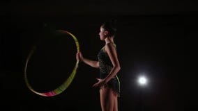L'atleta attraente sveglio esile della ragazza in costume da bagno variopinto luminoso esegue gli elementi della ginnastica ritmi L'atleta attraente sveglio esile della ragazza in costume da bagno variopinto luminoso esegue gli elementi della ginnastica ritmi