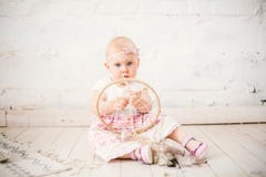 L'attrapeur rêveur d'amulette et le petit bébé un an avec des yeux bleus, blonde s'assied sur le plancher dans une robe et juge photographie stock libre de droits L'attrapeur rêveur d'amulette et le petit bébé un an avec des yeux bleus, blonde s'assied sur le plancher dans une robe et juge photographie stock libre de droits