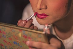 L'attrice cinese di opera sta dipingendo il suo fronte dietro le quinte fotografia stock L'attrice cinese di opera sta dipingendo il suo fronte dietro le quinte fotografia stock