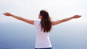 L'aumento della donna arma su alla scogliera contro il mare blu Mani outstretching del traveleer femminile stock footage L'aumento della donna arma su alla scogliera contro il mare blu Mani outstretching del traveleer femminile stock footage