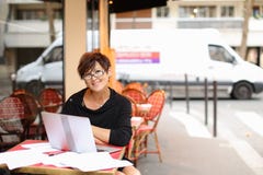 l'auteur féminin âgé travaillant avec le nouveau livre dans l'ordinateur portable et ont images stock l'auteur féminin âgé travaillant avec le nouveau livre dans l'ordinateur portable et ont images stock