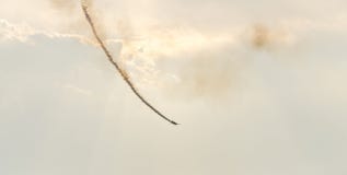 L'avion avec le vol coloré de fumée de trace dans le bleu opacifie les rayons acrobatiques aériens de ciel, d'exposition de casca Image libre de droits L'avion avec le vol coloré de fumée de trace dans le bleu opacifie les rayons acrobatiques aériens de ciel, d'exposition de casca Image libre de droits