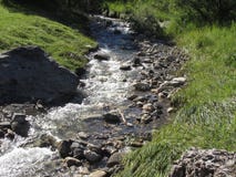 L'eau entrant et éclaboussant au-dessus des roches dans un courant de rivière de montagne photos stock L'eau entrant et éclaboussant au-dessus des roches dans un courant de rivière de montagne photos stock