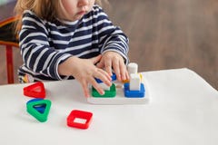 L'enfant 1,5 années se reposant à la table et jouant avec un jouet se développant, technique de Montessori, les mains du ` s d'en photographie stock libre de droits L'enfant 1,5 années se reposant à la table et jouant avec un jouet se développant, technique de Montessori, les mains du ` s d'en photographie stock libre de droits
