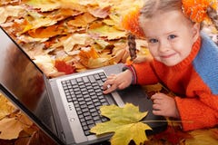 L'enfant de fille dans l'orange d'automne part avec l'ordinateur portatif. photographie stock libre de droits L'enfant de fille dans l'orange d'automne part avec l'ordinateur portatif. photographie stock libre de droits