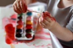 L'enfant de photo touche la brosse avec les mains sales dans la peinture sur un fond de peinture d'aquarelle photo libre de droits L'enfant de photo touche la brosse avec les mains sales dans la peinture sur un fond de peinture d'aquarelle photo libre de droits