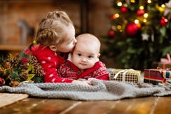 L'enfant en bas âge de petit garçon dans un chandail rouge embrasse sa soeur plus âgée, lyi image stock L'enfant en bas âge de petit garçon dans un chandail rouge embrasse sa soeur plus âgée, lyi image stock