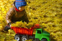 L'enfant joue avec une machine de jouet en parc d'automne photos stock L'enfant joue avec une machine de jouet en parc d'automne photos stock
