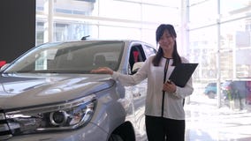 L'esposizione automatica, ritratto della donna asiatica sorridente del venditore dell'automobile presenta la nuova automobile all L'esposizione automatica, ritratto della donna asiatica sorridente del venditore dell'automobile presenta la nuova automobile all