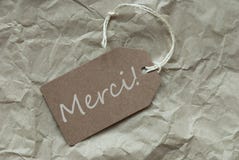 L'etichetta beige con i mezzi di Merci del francese vi ringrazia fondo di carta fotografia stock L'etichetta beige con i mezzi di Merci del francese vi ringrazia fondo di carta fotografia stock