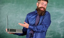 L'expression confuse par professeur de hippie tient l'ordinateur portable Questions de formation à distance Questions de enseigne photographie stock L'expression confuse par professeur de hippie tient l'ordinateur portable Questions de formation à distance Questions de enseigne photographie stock