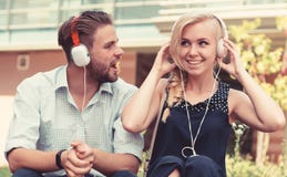 L'homme avec la femme apprécient la musique extérieure avec le fond urbain, defocused photographie stock L'homme avec la femme apprécient la musique extérieure avec le fond urbain, defocused photographie stock
