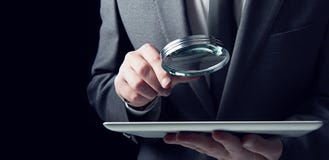 L'homme d'affaires examine un comprimé avec une loupe Concept de sécurité d'Internet image libre de droits L'homme d'affaires examine un comprimé avec une loupe Concept de sécurité d'Internet image libre de droits