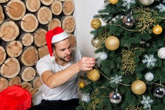 L'homme dans le chapeau du père noël décorent l'arbre de Noël Photos stock L'homme dans le chapeau du père noël décorent l'arbre de Noël Photos stock