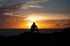 L'homme de silhouette s'assied sur une falaise images libres de droits L'homme de silhouette s'assied sur une falaise images libres de droits