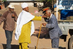 L'homme embrasse la croix à la main d'un prêtre orthodoxe à la rue dans Lalibela, Ethiopie image stock L'homme embrasse la croix à la main d'un prêtre orthodoxe à la rue dans Lalibela, Ethiopie image stock
