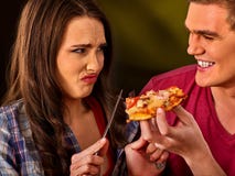 L'homme et la femme mangent de la pizza de tranche avec le couteau et la fourchette photographie stock L'homme et la femme mangent de la pizza de tranche avec le couteau et la fourchette photographie stock