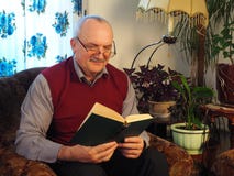 L'homme plus âgé avec un livre dans une chaise images libres de droits L'homme plus âgé avec un livre dans une chaise images libres de droits