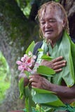 L'homme âgé d'antan d'habitant des îles du Pacifique regarde la fleur exotique sur le tou d'eco images stock L'homme âgé d'antan d'habitant des îles du Pacifique regarde la fleur exotique sur le tou d'eco images stock